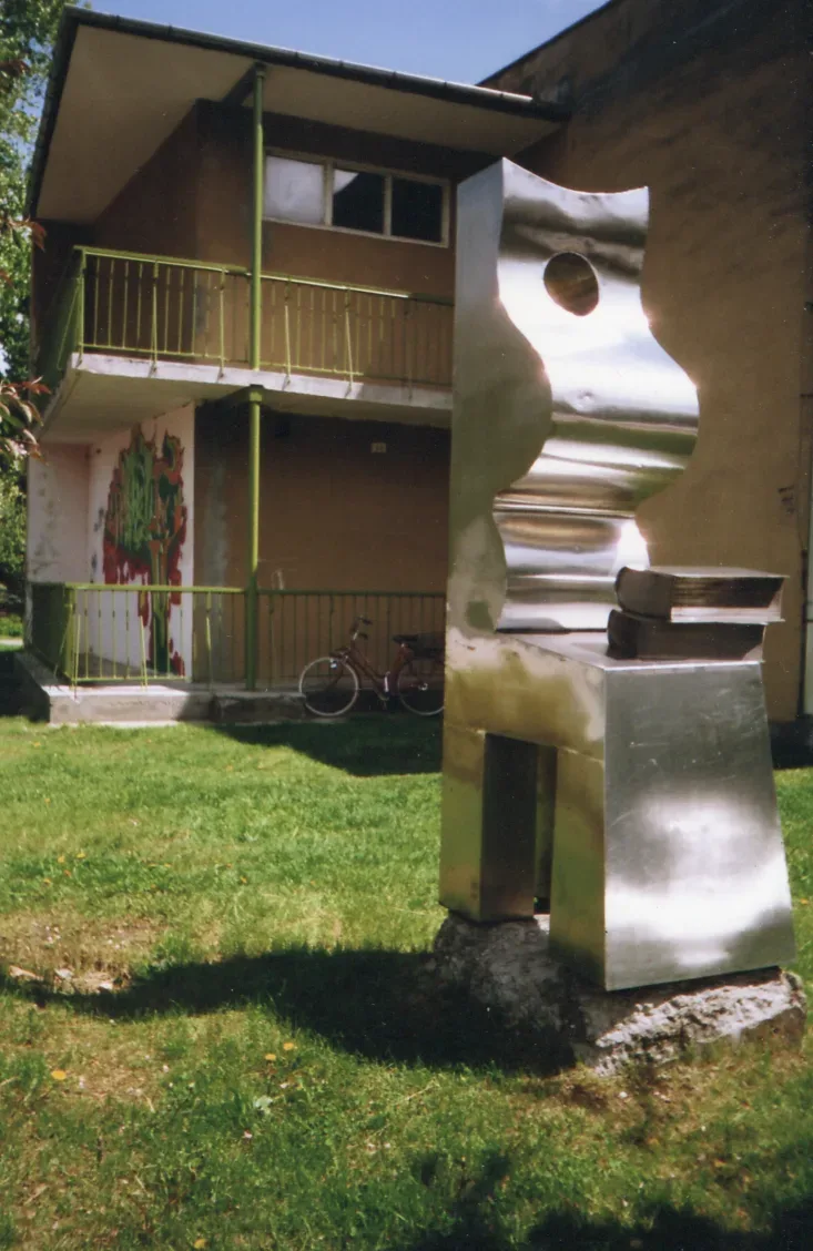 Matka z książką: scultura in acciaio inox davanti a una biblioteca