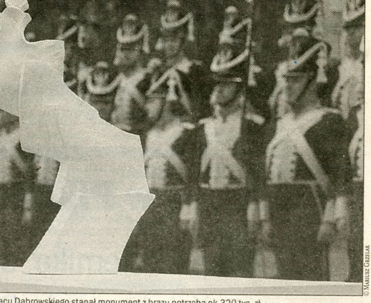 Fotografia di giornale: il modello in gesso del monumento, quattro forme ondulate che salgono verso l’alto, ripreso sulla piazza davanti ai musicisti in uniforme storica di una banda militare