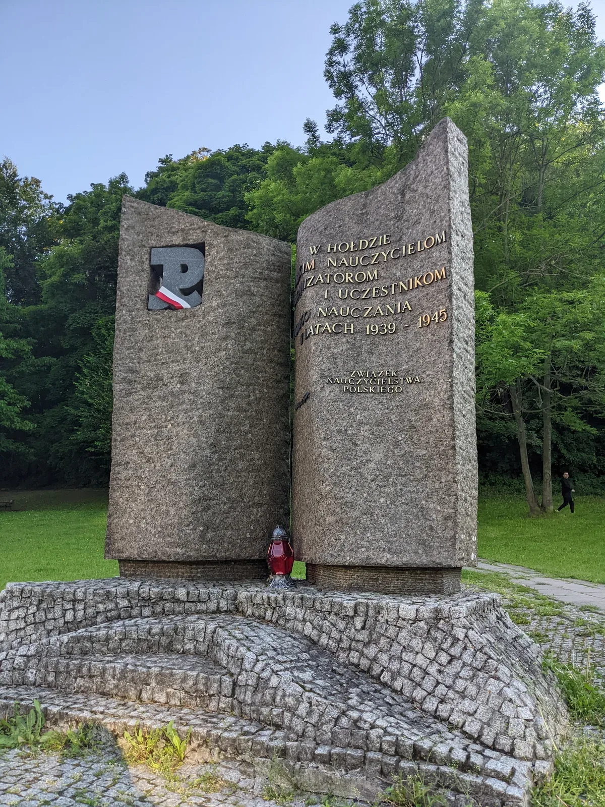 Il monumento con un nastro bianco e rosso passato dentro la finestra e un lume acceso ai piedi della fenditura
