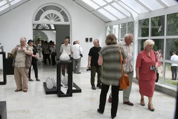 La galleria Oranżeria col pubblico: visitatori fra i plinti neri sotto il tetto a vetri, una forma ovoidale bianca su un plinto.