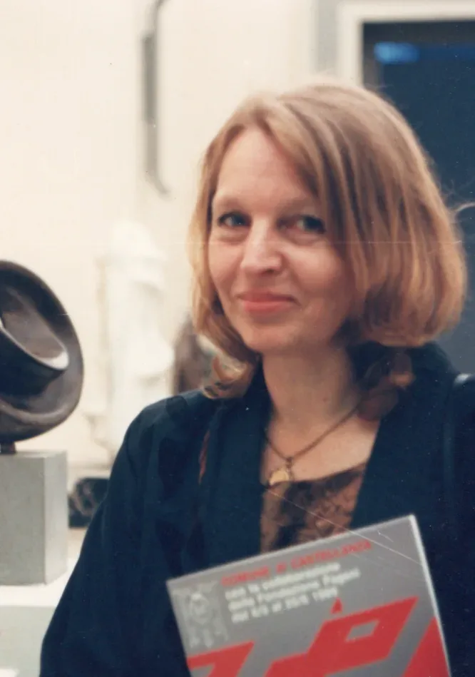 Antonina appoggiata allo stipite di una sala d’esposizione; dietro di lei una fila di plinti bianchi con piccole sculture